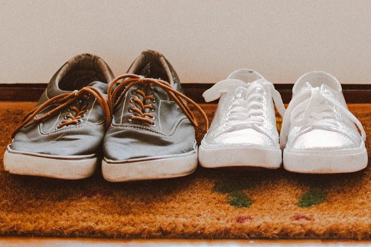 Welcome mat with shoes Floor mat with brown leather shoes and adjacent white sneakers